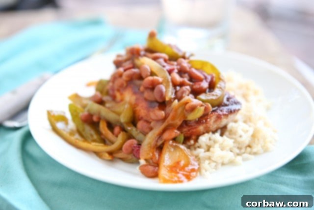 Grilled Pork Chops smothered in a special sauce made with baked beans, peppers and onions. So flavorful and an easy dinner to make - perfect for grilling season! A vibrant and delicious plate featuring smothered grilled pork chops alongside a healthy serving of brown rice, showcasing the perfect family dinner combination.