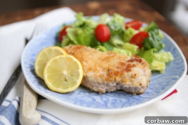 Parmesan crusted pork chops baked to perfection, served with a fresh lemon wedge and green salad