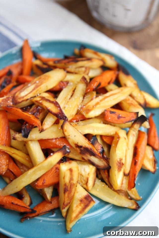 Honey Roasted Parsnips and Carrots: A Sweet and Savory Fall Favorite Close-up of golden brown honey roasted parsnip and carrot sticks on a blue plate, garnished with fresh herbs
