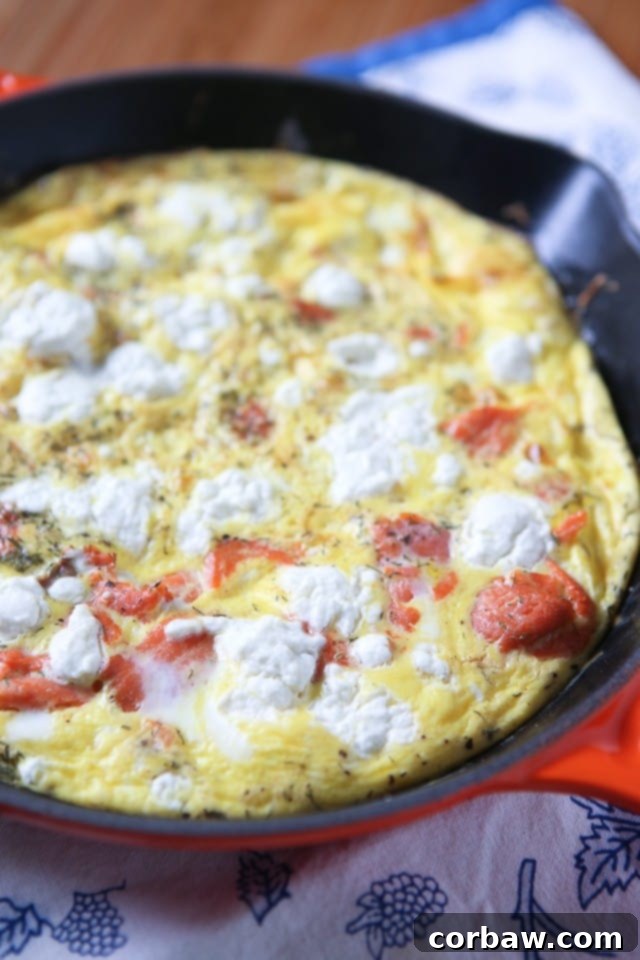 Smoked Salmon Frittata A golden-brown smoked salmon frittata in a cast-iron skillet, topped with cheese and fresh dill, ready to be served for breakfast, brunch, or dinner.