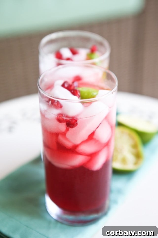 A beautifully garnished Pomegranate Rum Cocktail, perfect for a festive occasion or a relaxing evening, showcasing its vibrant red hue and fresh lime.