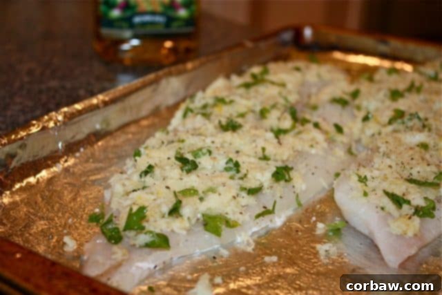 Close-up shot of raw fish fillets generously covered with a golden breadcrumb, herb, and lemon topping, ready for baking.