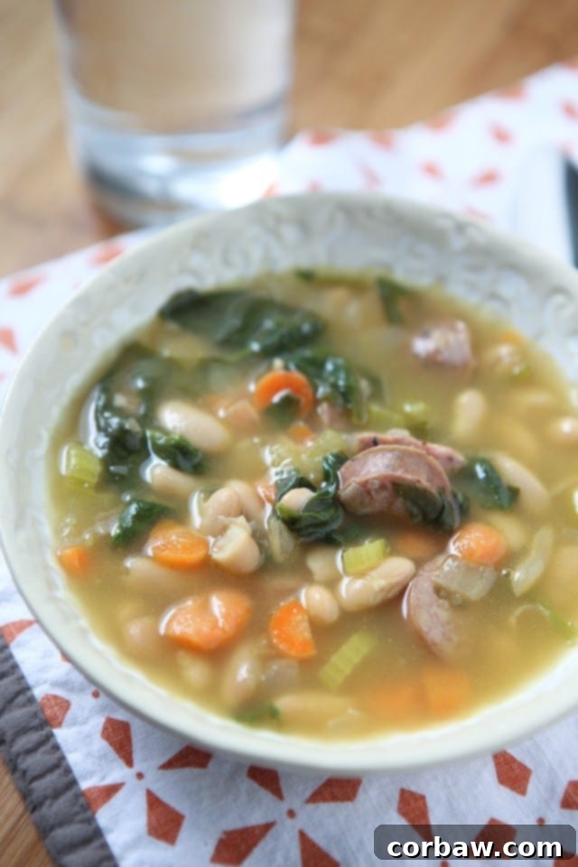 It's definitely soup season and one of my family's favorite soups is this Smoked Sausage and White Bean Soup with Spinach. It will warm you right up! #soup #healthyrecipe #healthysoup A comforting bowl of Smoked Sausage and White Bean Soup with Spinach, featuring tender chicken sausage, creamy beans, and wilted spinach in a rich broth.