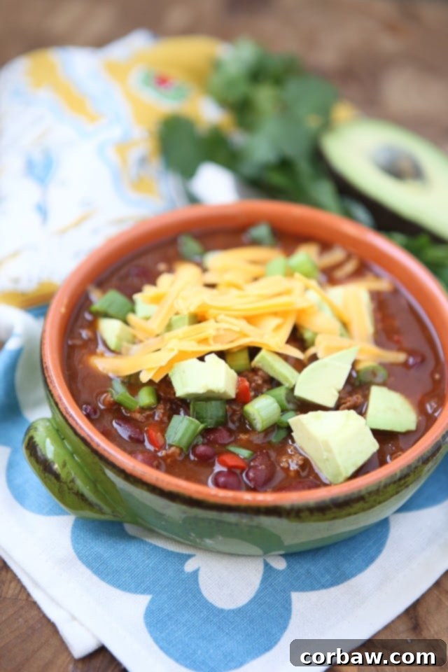 Chipotle Chicken Chili bowl of chili topped with shredded cheese, avocado, and scallions