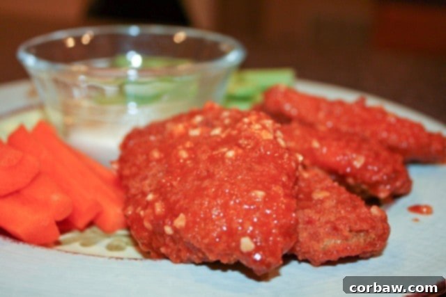 Baked Boneless Chicken Wings - Your Healthy Indulgence A vibrant plate of hot and garlicky baked boneless chicken wings, served with fresh celery and carrot sticks, and a side of creamy blue cheese dressing for dipping. A perfect, guilt-free comfort food.