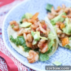 Two vibrant shrimp tacos with mango salsa and avocado on a plate.