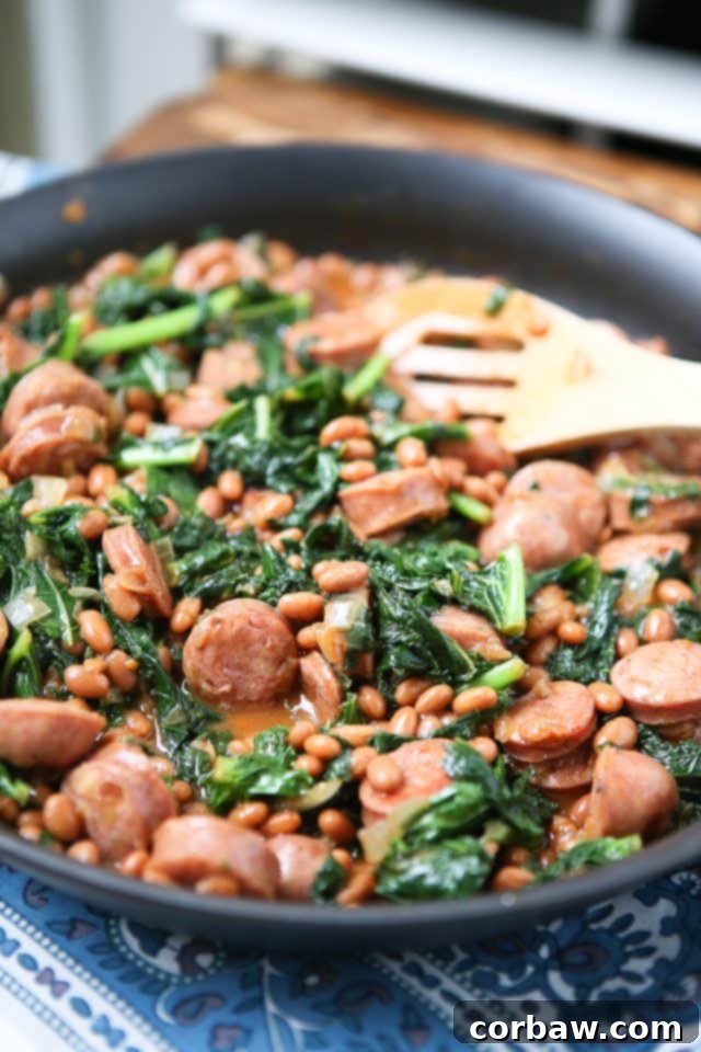 Delicious one-pan skillet with savory baked beans, tender chicken sausage, and fresh green kale, ready to serve as a quick weeknight meal.