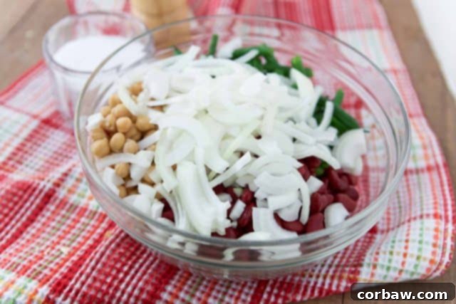 A close-up view of the ingredients for the three bean salad dressing, showing a small saucepan with apple cider vinegar, oil, sugar, and spices, ready to be simmered to create the flavorful marinade.