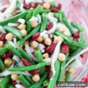 A delicious homemade Three Bean Salad with Vidalia Onions in a clear bowl, perfect for picnics and BBQs.