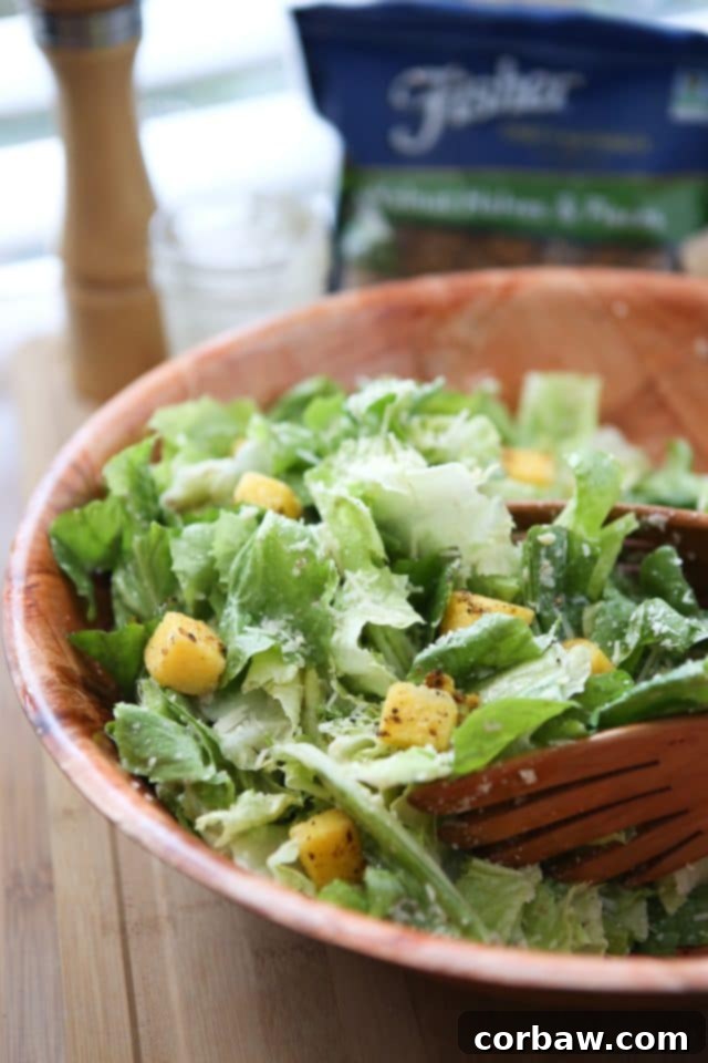 A generous wooden bowl presenting the completed Escarole Caesar Salad, artfully garnished with golden Polenta Croutons and a final drizzle of the exquisite Parmesan Walnut Lemon Vinaigrette. This gourmet salad is ready to serve and impress for any meal.
