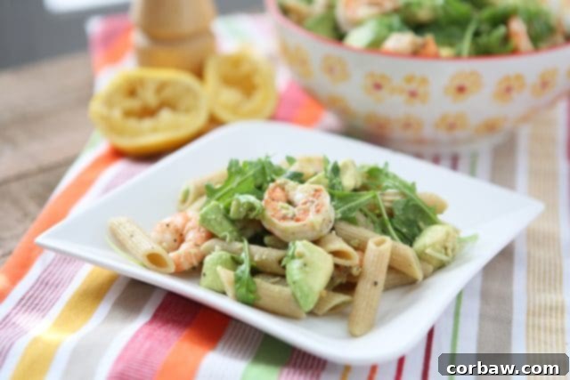 plate of whole wheat pasta topped with shrimp, arugula, and diced avocado