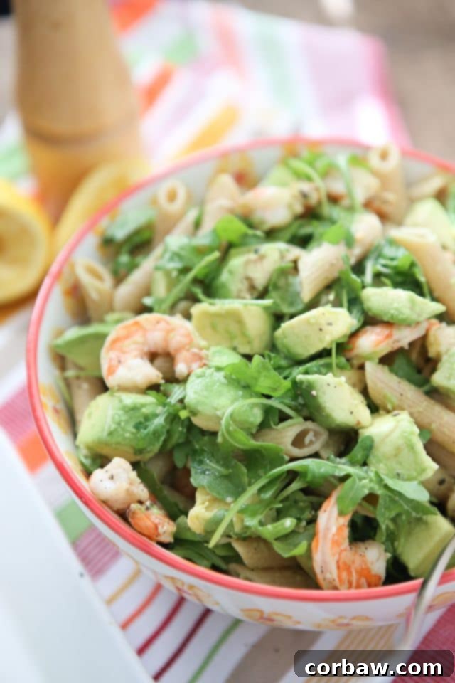 plate of whole wheat pasta topped with shrimp, arugula, and diced avocado