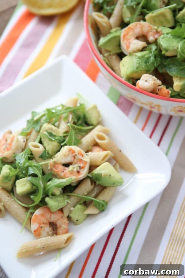 plate of whole wheat pasta topped with shrimp, arugula, and diced avocado