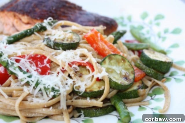 Spring's Bounty Whole Wheat Linguine 2 A vibrant bowl of Linguine with Spring Vegetables, featuring whole wheat pasta, fresh zucchini, asparagus, and red bell peppers, garnished with Parmesan cheese. Ideal as a light main or a healthy side dish.