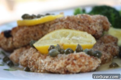 A single serving of chicken piccata, topped with lemon slices and capers, garnished with fresh parsley on a white plate.