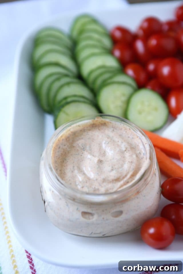 A vibrant bowl of Chipotle Ranch Greek Yogurt Dip surrounded by colorful fresh vegetables and crackers, ready for summer snacking.