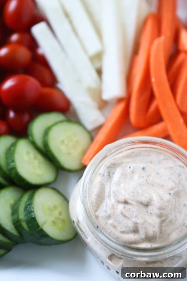 A close-up shot of a spoon scooping the creamy Chipotle Ranch Greek Yogurt Dip from a bowl.