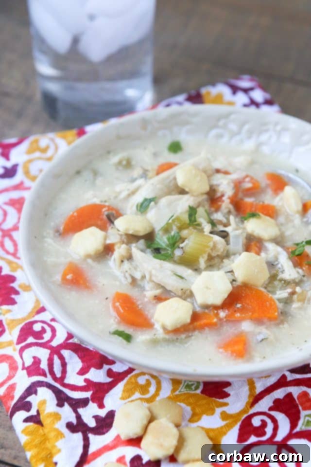 Hearty Slow Cooker Creamy Chicken and Wild Rice Soup for Busy Families A warm, inviting bowl of Slow Cooker Creamy Chicken and Wild Rice Soup, garnished with fresh parsley, highlighting its hearty texture and wholesome ingredients. Perfect for a cozy family dinner on a busy school night.