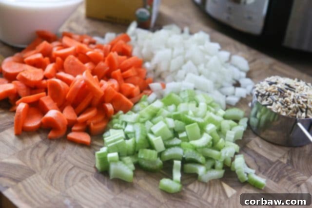 Preparing Healthy Chicken and Wild Rice Soup Ingredients A vibrant mix of chopped carrots, celery, and onions, ready to be added to the slow cooker for a batch of homemade creamy chicken and wild rice soup – the foundation of a flavorful meal.
