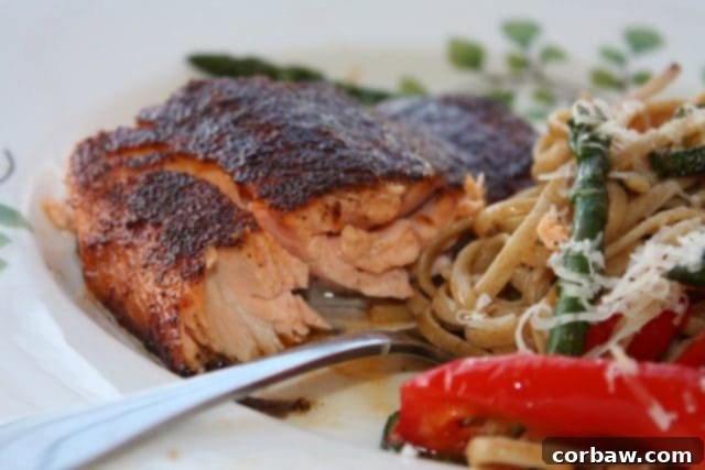 Healthy Sweet and Spicy Salmon: Easy Broiled or Grilled Salmon for Your Family Perfectly broiled salmon fillet with a sweet and spicy rub, served on a white plate with fork and a side of pasta and vegetables