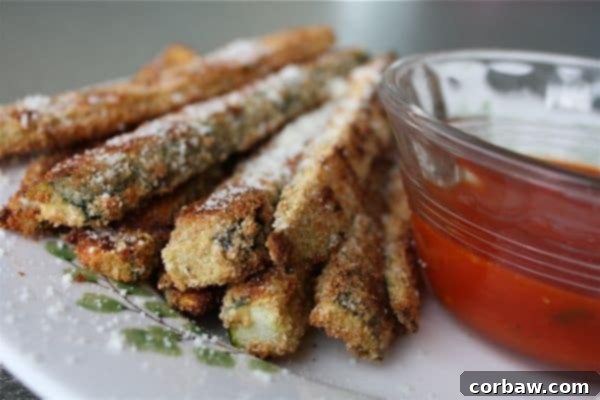 Serve these golden brown Oven Baked Parmesan Zucchini Sticks with marinara for a perfect snack! A serving of crispy oven baked Parmesan zucchini sticks with a bowl of marinara sauce.