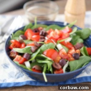 A top-down view of a vibrant chopped tomato and spinach salad, artfully arranged in a white bowl, hinting at its fresh and healthy ingredients.