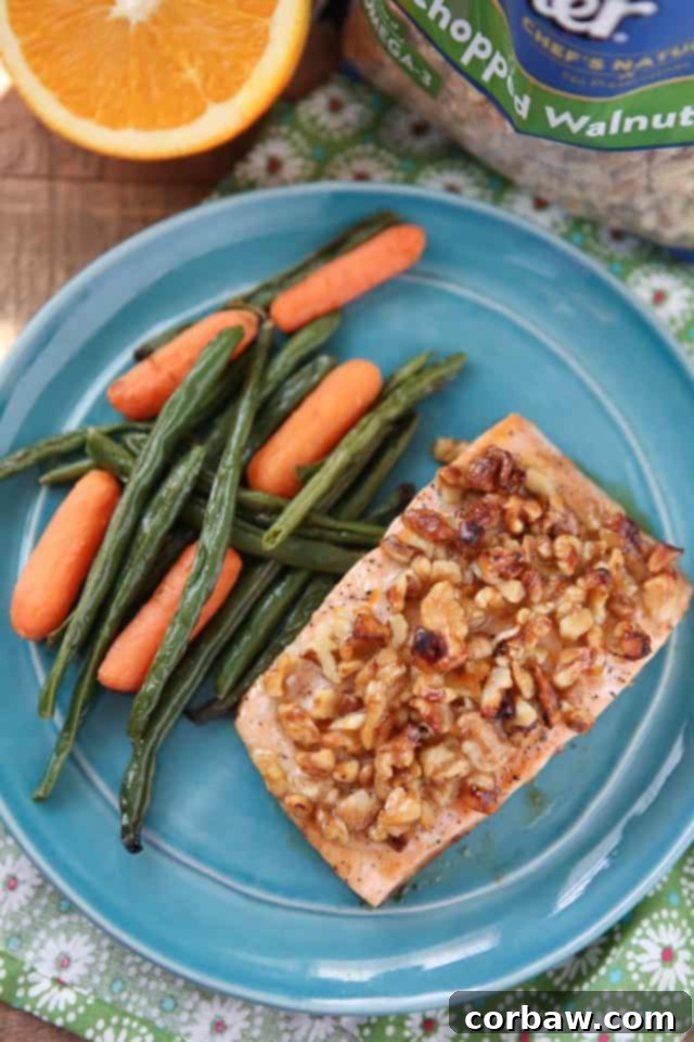 A serving of Orange Walnut Crusted Salmon garnished with fresh orange slices and herbs, on a plate.
