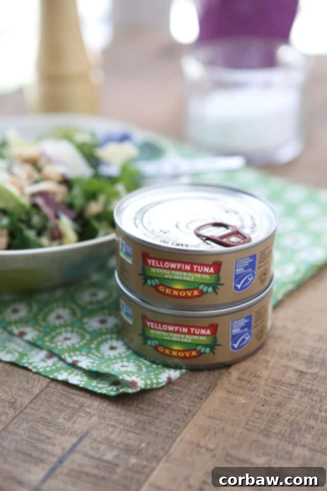 A close-up of the Lemony Tuna and White Bean Kale Salad being tossed, showing the fresh lemon juice and rich olive oil dressing. #tuna #kale #salad #avocado #LowCarb #saladrecipe