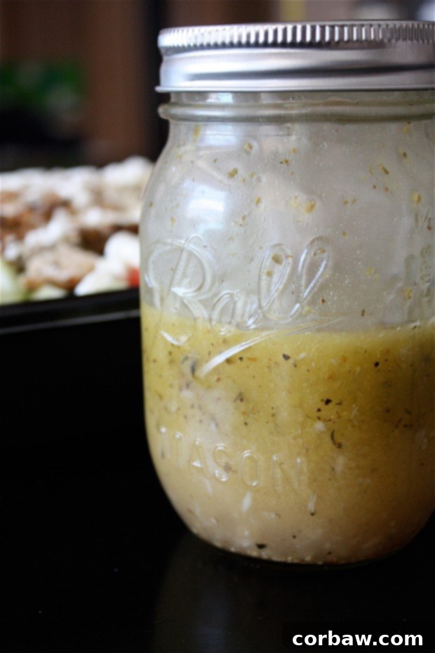 Versatile Greek Lemon Vinaigrette A captivating close-up of a glass jar filled with the homemade Greek Lemon Vinaigrette, showcasing its vibrant color and the texture of its fresh ingredients, prepared to elevate any meal with Mediterranean zest.