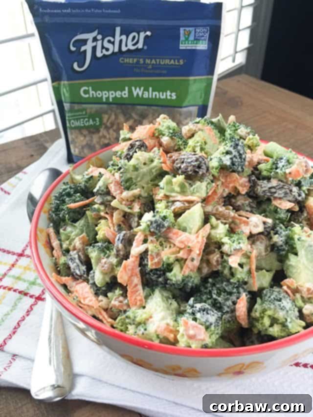 A vibrant bowl of broccoli raisin salad with walnuts, ready to be served as a healthy and delicious side dish for a gathering.