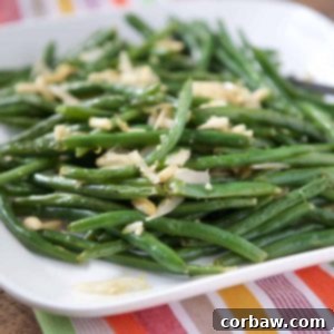Roasted green beans with almonds on a white platter.