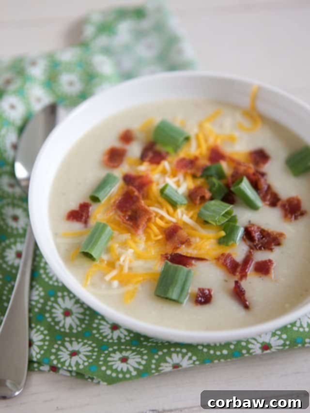 Creamy Slow Cooker Cauliflower Potato Soup 8 white bowl filled with creamy cauliflower potato soup topped with cheese, green onion, and crispy bacon