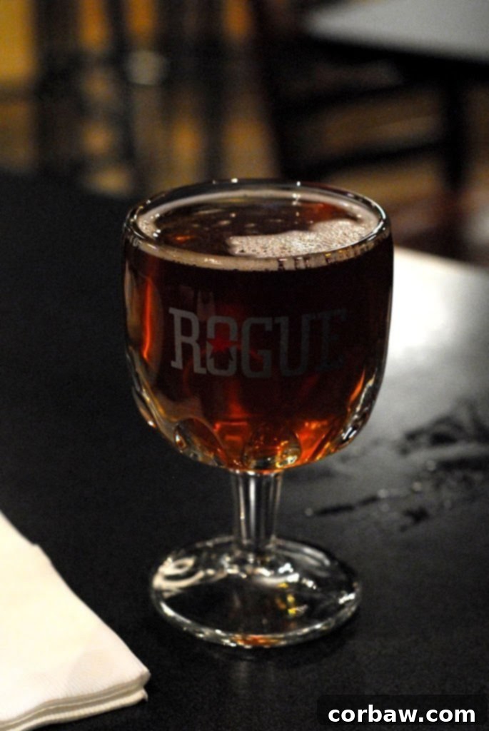 A close-up of a glass of dark beer, possibly an IPA, with a rich, foamy head.