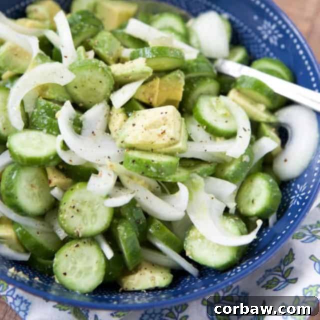 A close-up view of the vibrant and refreshing cucumber, avocado, and thinly sliced red onion salad, beautifully arranged in a blue ceramic bowl, highlighting the fresh textures and colors, ready to be enjoyed as a light and healthy meal or side.