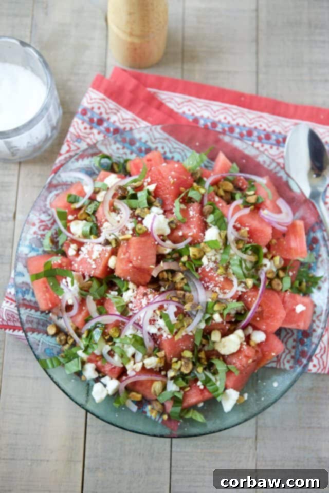 A beautifully presented Watermelon Feta Salad with fresh basil, red onion, and pistachios in a white bowl, ready to be served as a refreshing summer side dish.