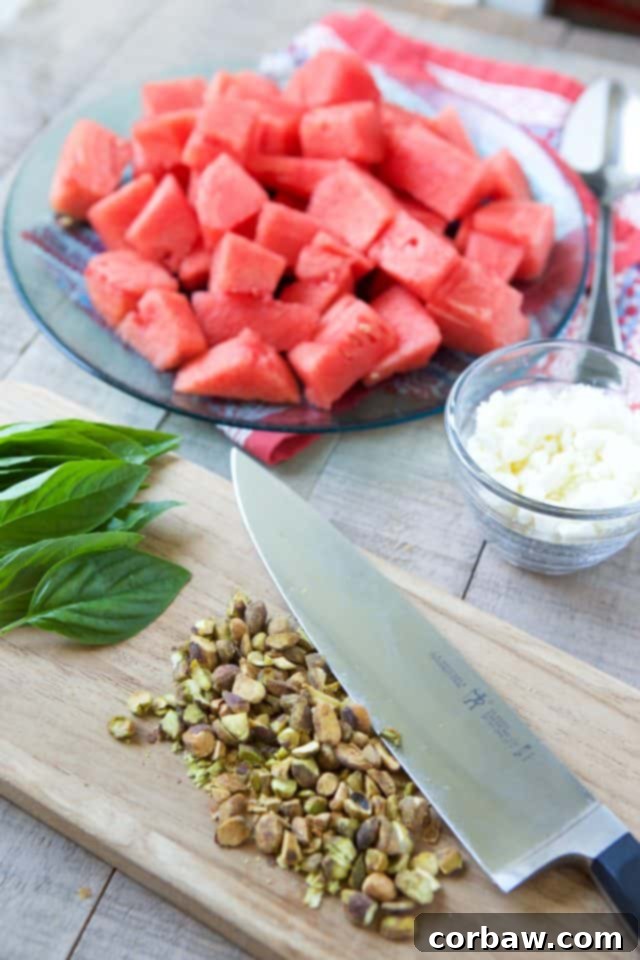 A vibrant bowl of Watermelon Feta Salad with fresh basil, pistachios, and red onion, glistening with balsamic vinegar, ready to be served.
