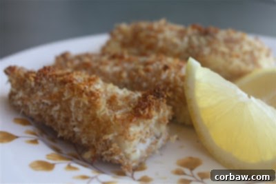 Plate of golden-brown crispy baked fish fingers with lemon wedges