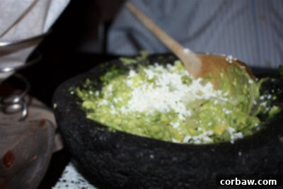 A vibrant array of fresh ingredients for guacamole, including avocados, limes, cilantro, and serrano chiles