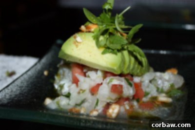 An exquisite plate of red snapper ceviche, beautifully presented with avocado, tomato, onion, cilantro, and lime