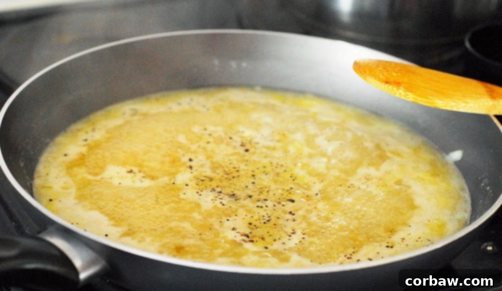 Chicken broth simmering gently in a small saucepan on the stove.