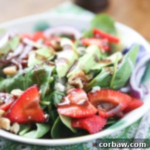 A vibrant Strawberry Spinach and Walnut Salad with homemade Raspberry Balsamic Vinaigrette, featuring fresh greens, bright berries, and crunchy nuts, a healthy and delicious meal option.