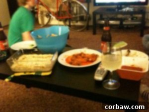 A partially eaten platter of food, including chicken legs and dip, from a game day party.