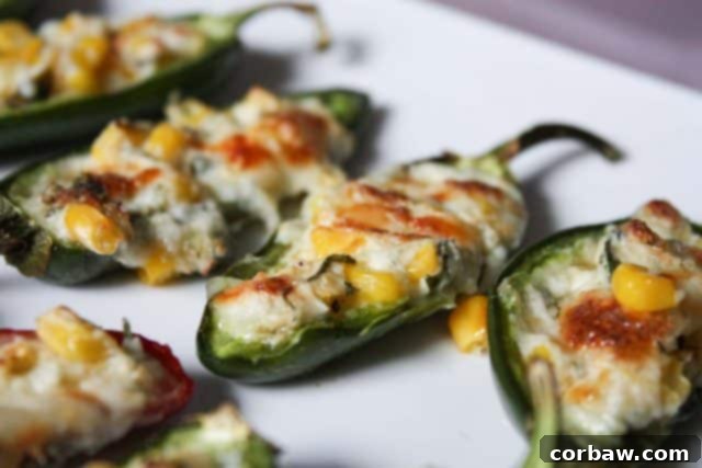 Baked cream cheese and corn stuffed jalapenos arranged on a white serving plate