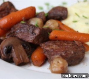 Slow Cooker Beef Bourguignon in a white bowl with mashed potatoes