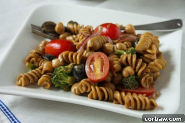 pasta salad with cherry tomatoes, olives, red onions, and broccoli on a plate with a fork