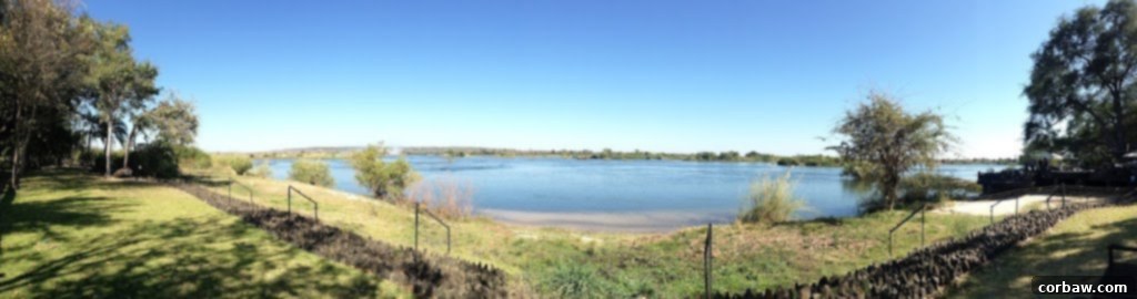 View of the Zambezi River with hippos in the distance from the Royal Livingstone Hotel dock, a serene scene.