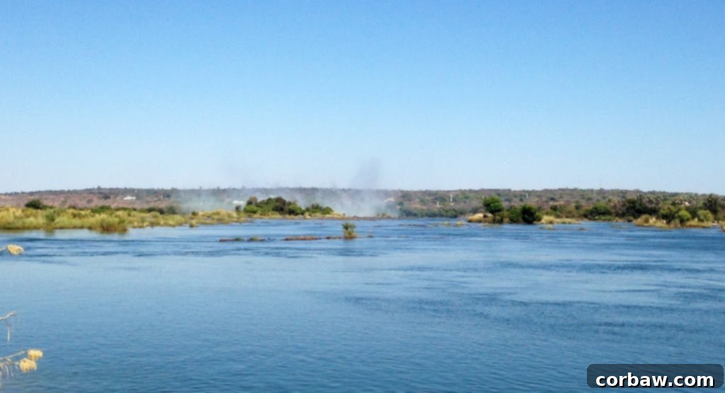 Mist and spray from Victoria Falls seen from the boat approaching Livingstone Island, a powerful visual.