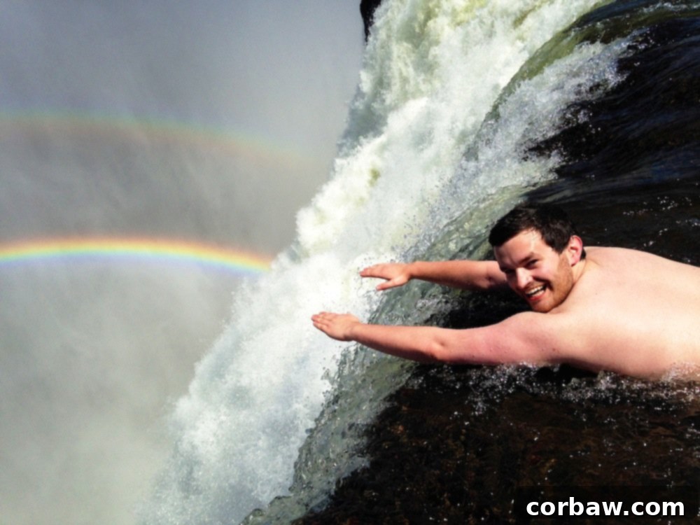 Fiancé striking a Superman pose in Devil's Pool at Victoria Falls, embracing the thrilling experience.