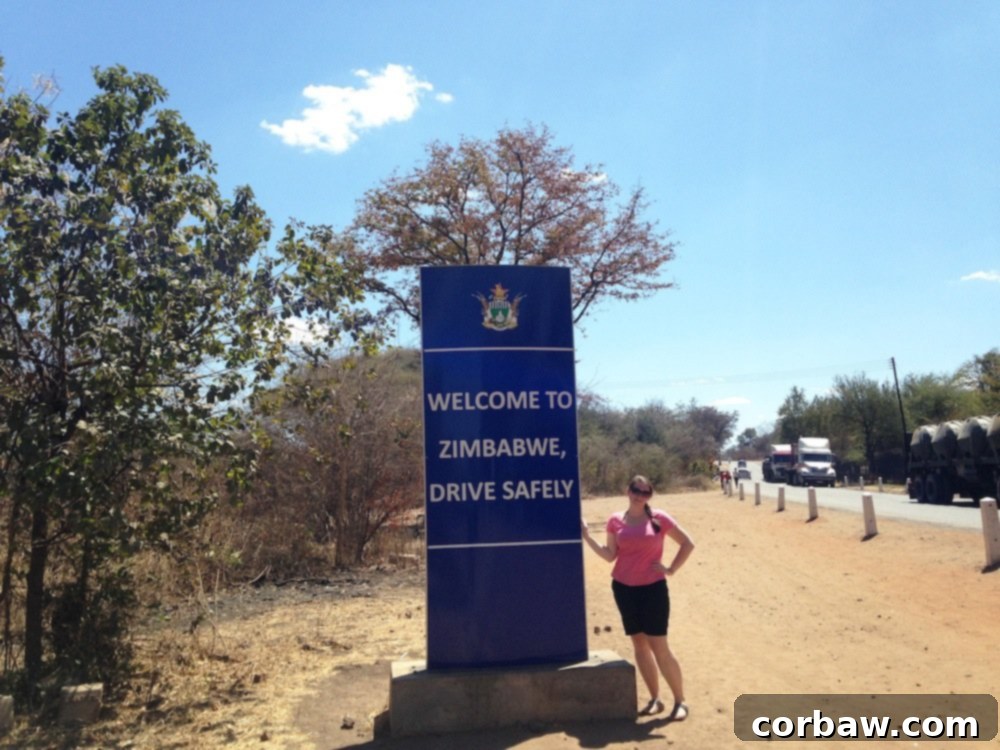 Author posing for a tourist photo with the Victoria Falls National Park sign in Zimbabwe, a memorable moment.
