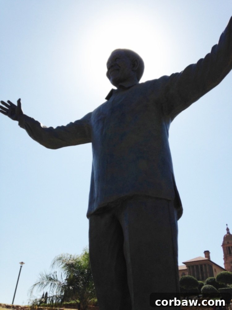 Woman standing next to a large bronze Nelson Mandela statue at the Union Buildings in Pretoria
